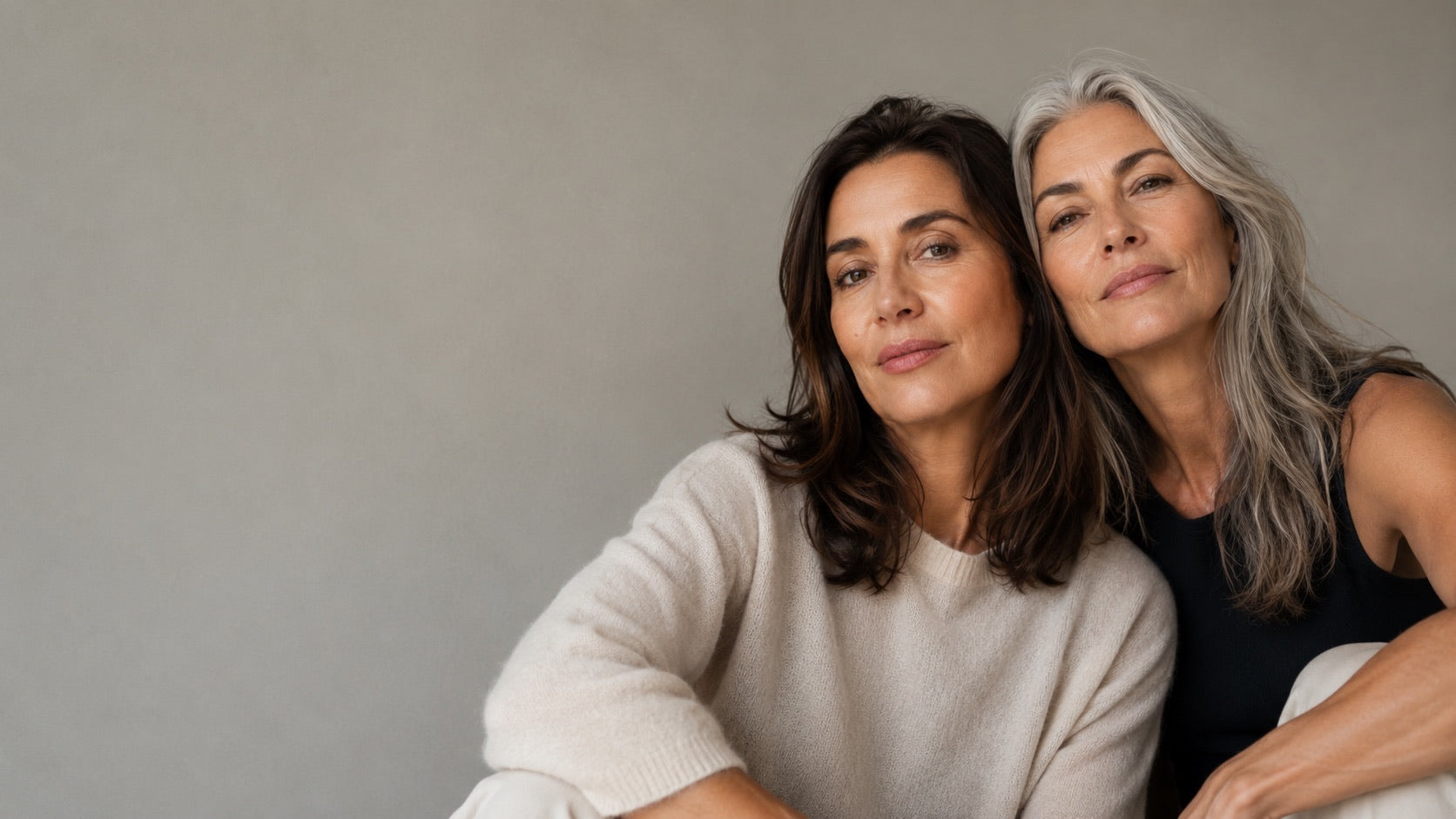 Twee vrouwen naast elkaar tegen een warmgrijze muur
