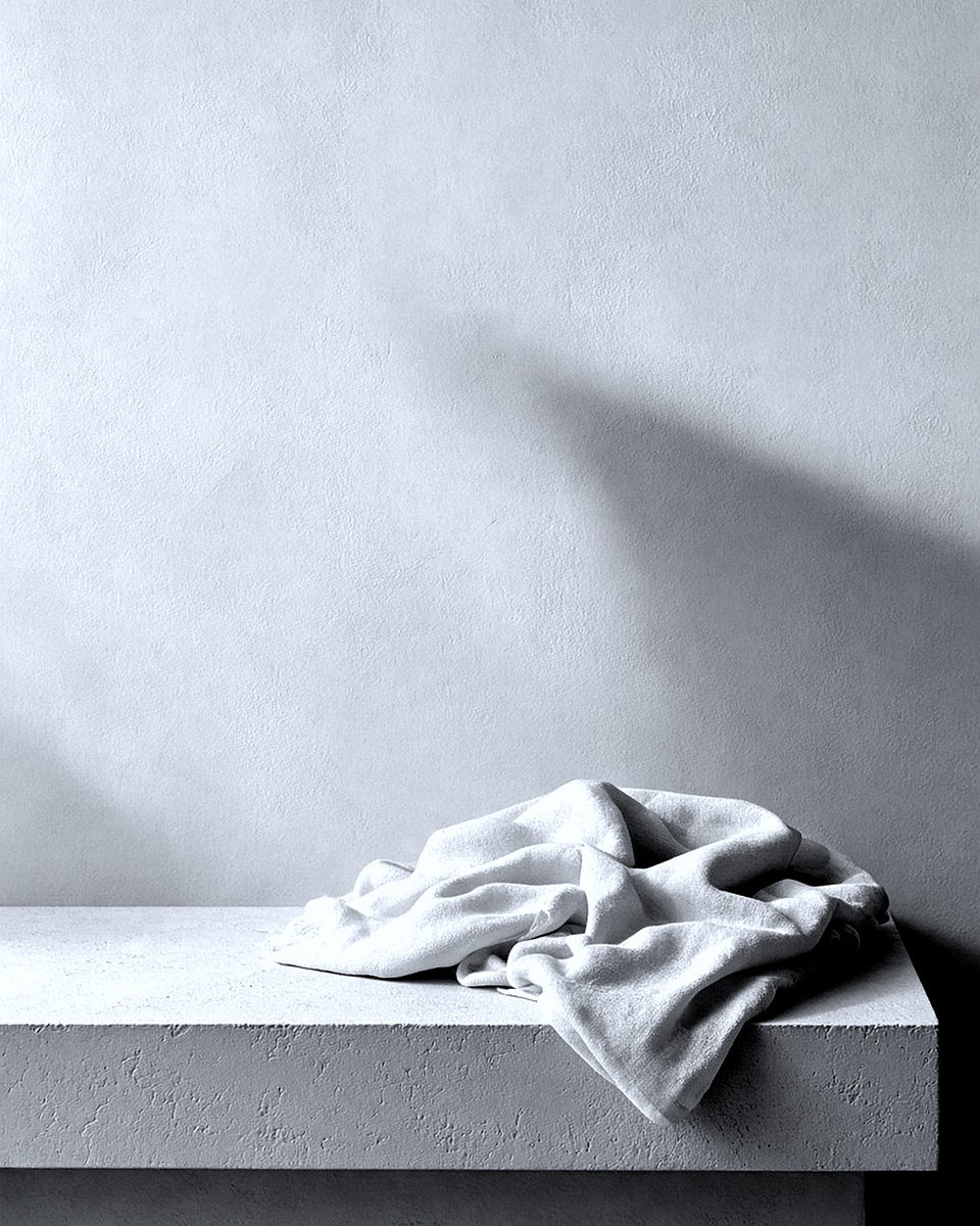 Stilleven in zwart-wit: een witte gevouwen doek op een licht vlak